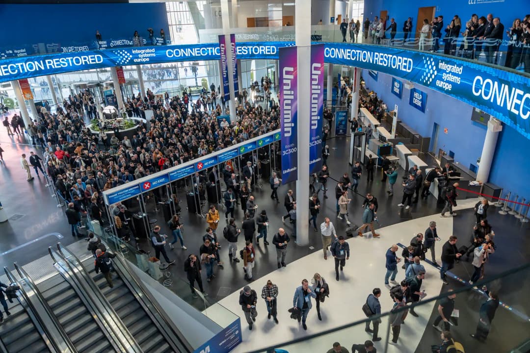 A crowded convention center with people walking and gathering under banners reading "CONNECTION RESTORED." The scene is busy and bustling.